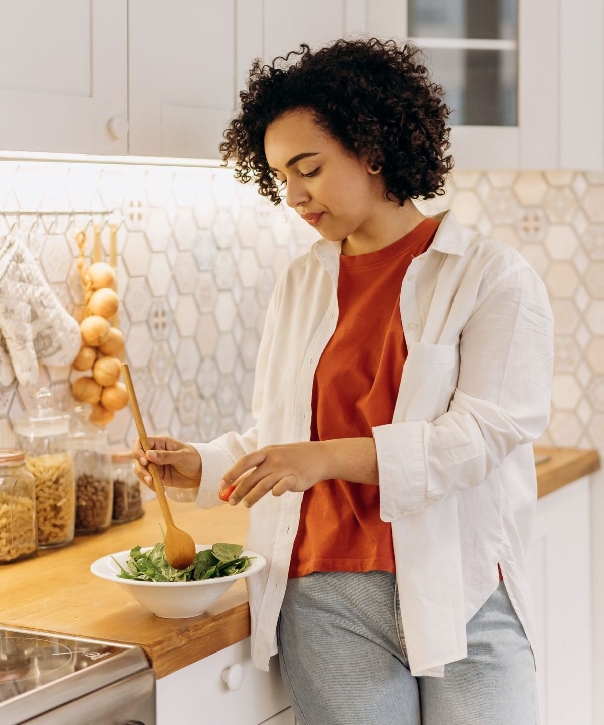 Mulher preparando uma salada fresca na cozinha, representando mudanças de hábitos alimentares